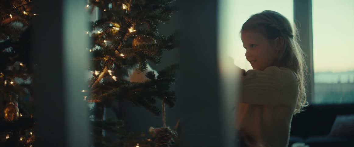 Blonde girl decorates christmas tree in room