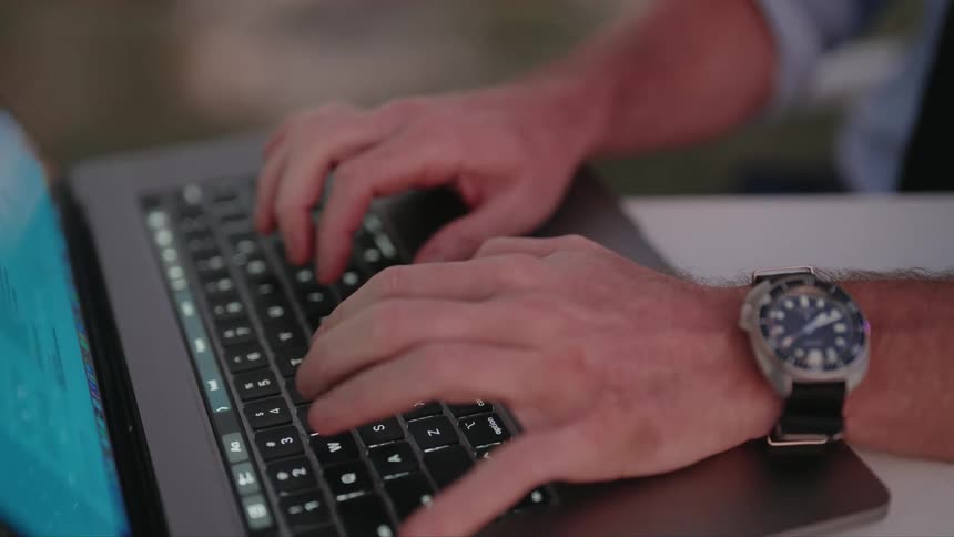 A mans hands as he types on a laptop