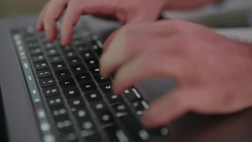 A mans hands as they type on a laptop