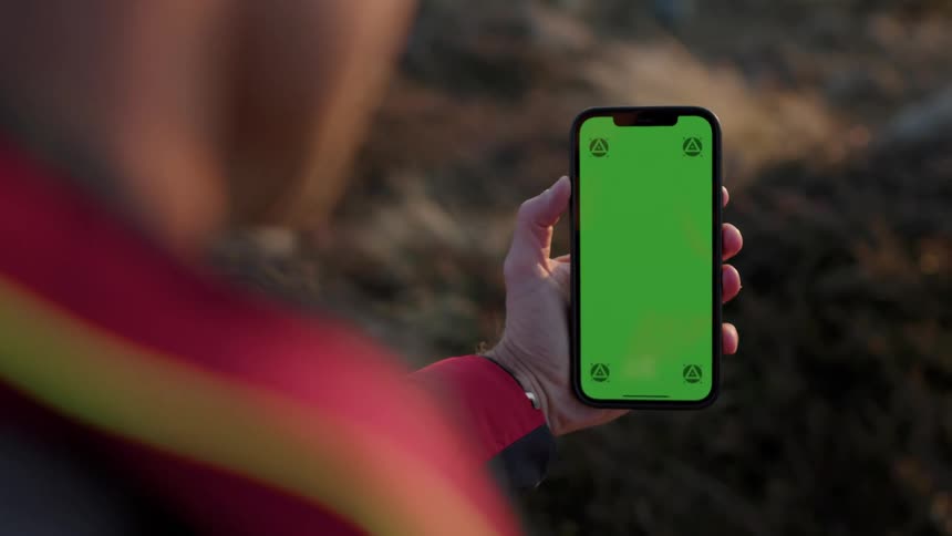 A man holds his phone out to use it outdoors