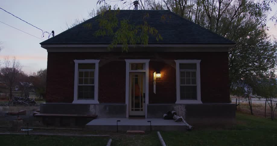 The porch light of a small house is on near the front door