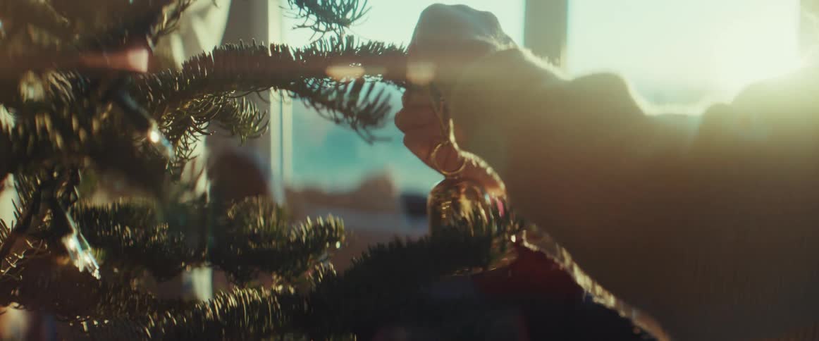 A girl hangs a bell as a christmas tree ornament