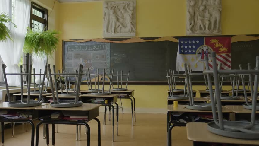 Stools are on top of the desks in an empty classroom