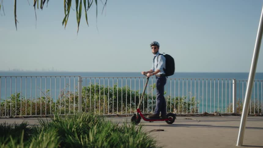 A man is riding his scooter past the coast