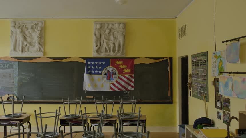 Stools are on top of the desks in an empty classroom