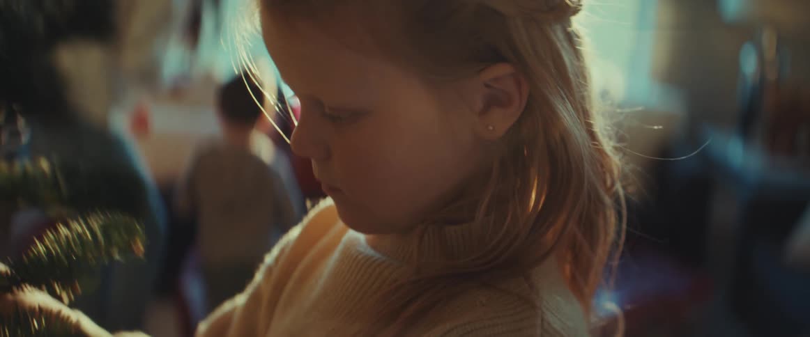 A girl decorates the christmas tree while her mom helps her brothers