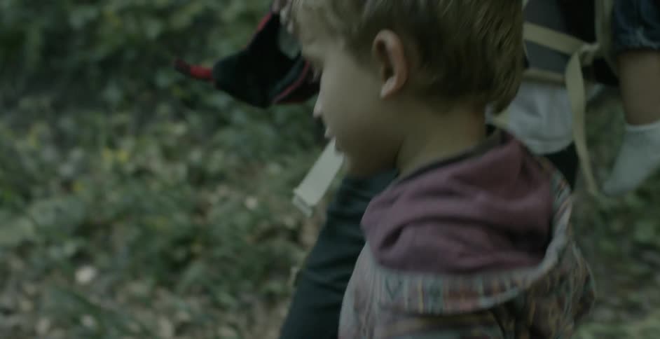 A kid walks next to his parents on a trail