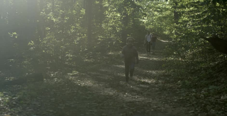 A boy runs down a forest path