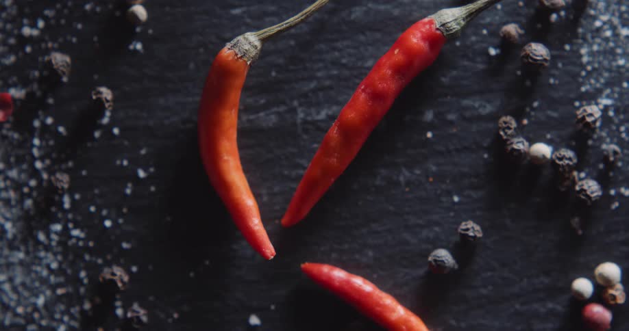 Chili peppers are surrounded by peppercorns and flaked salt