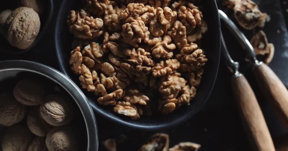 A nutcracker is next to a bowl of walnuts with their shell removed