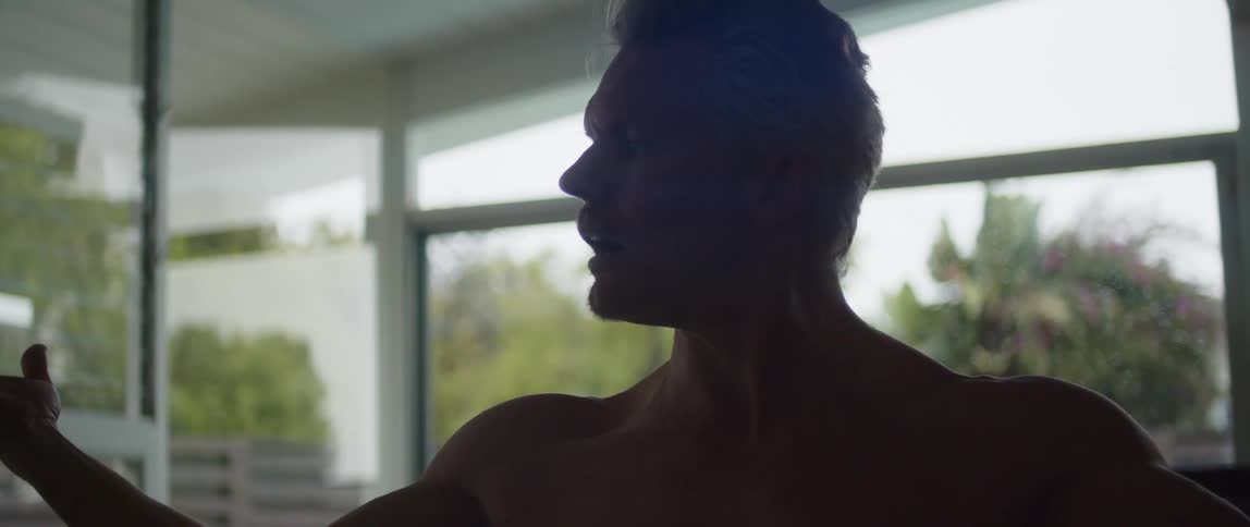 A man is stretching his arms while standing indoors