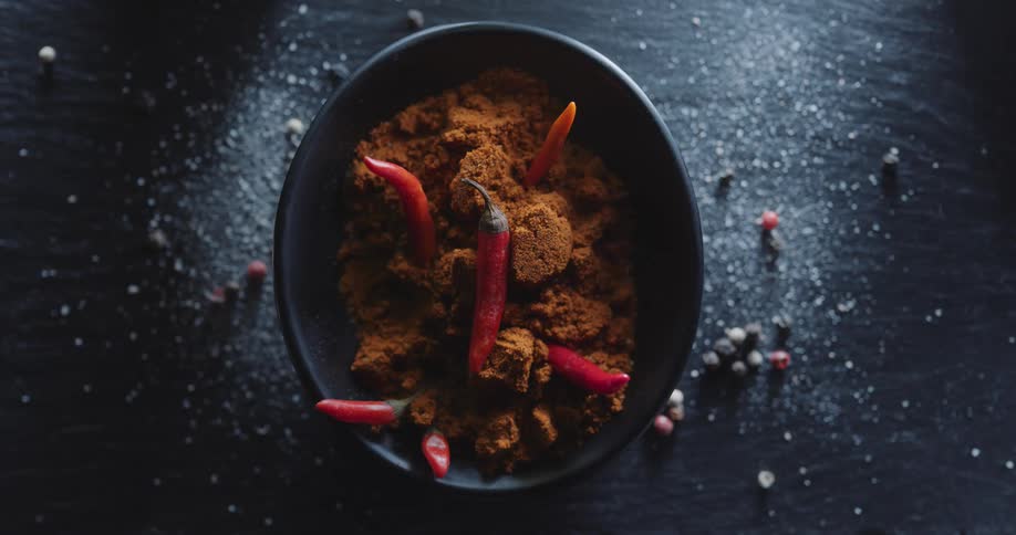 A bowl with chilies and spices on a counter