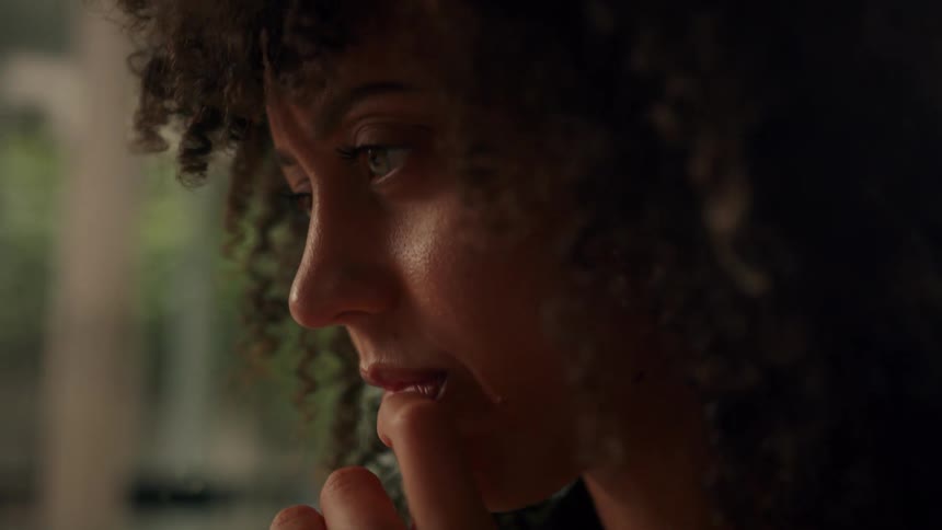 A woman has her finger in her mouth and she nods her head