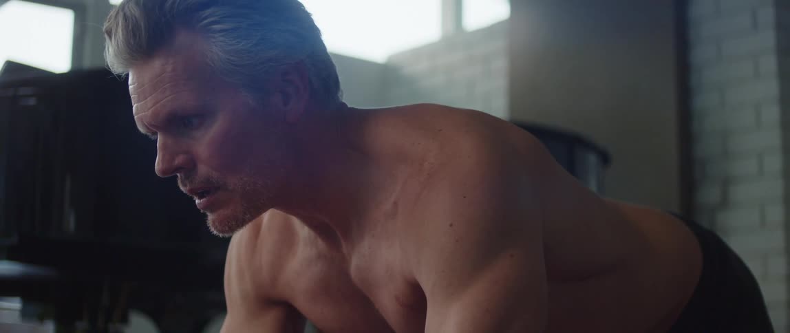 Topless man does push ups near the grand piano in room