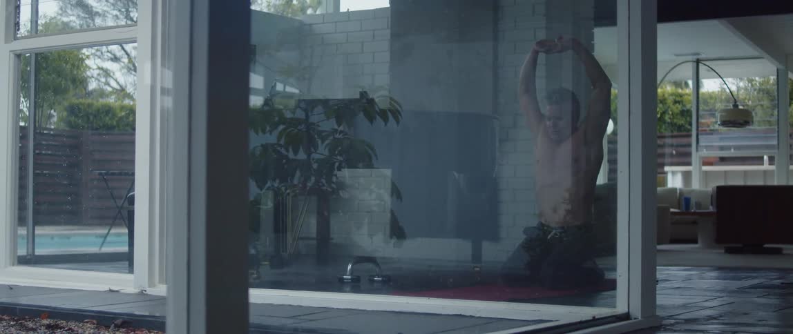 A man stretches his arms while doing yoga at home
