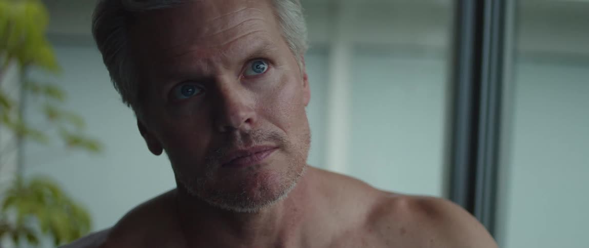 A man without a shirt on looks around at home