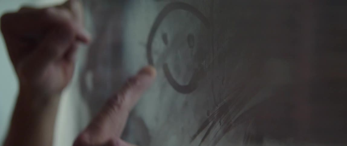 Someone draws a smiley face on the window condensation with their finger and then wipes it away with their hand
