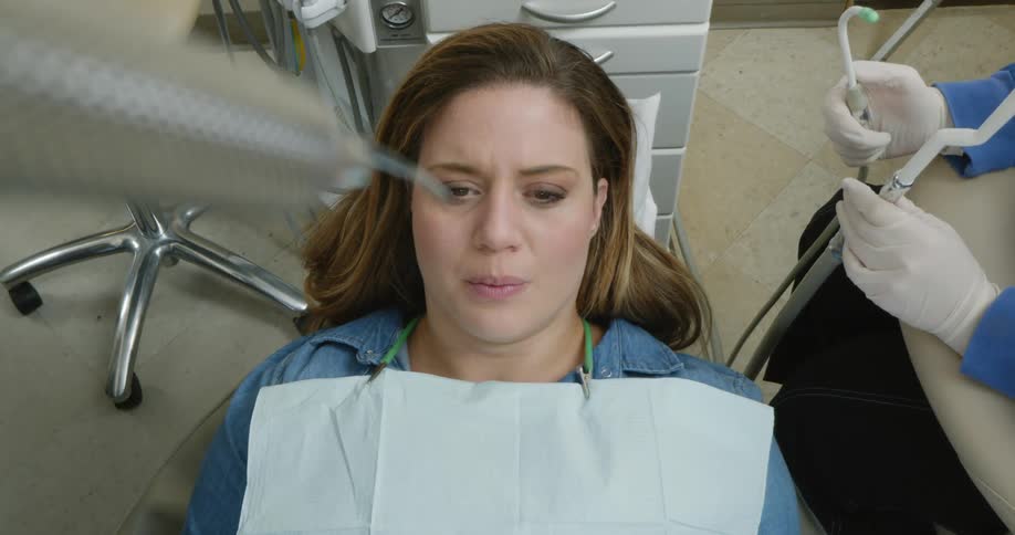 A patient speaks to her dentist while lying in a chair