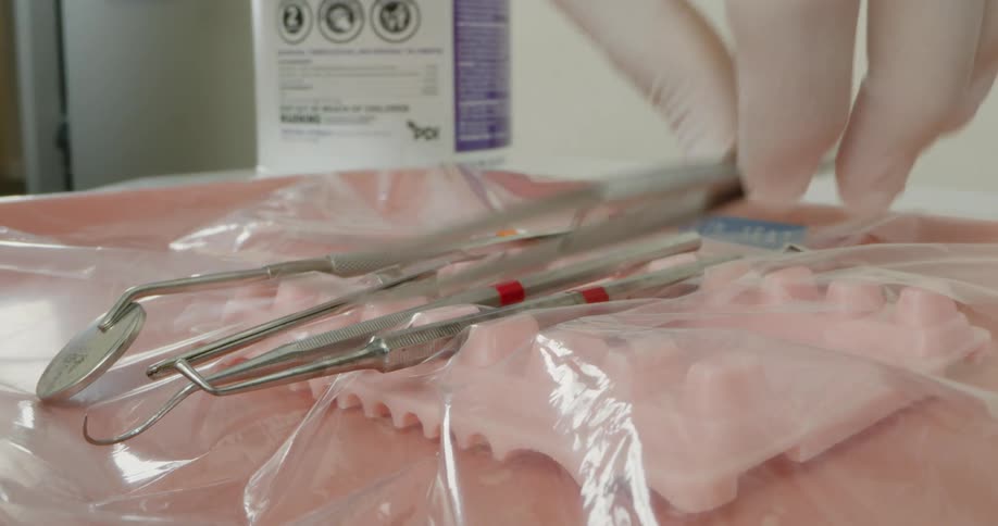 Dental professional picks up tweezer from group of dental instruments