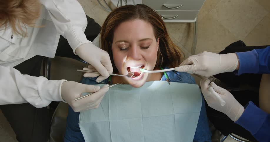 Dentist treats female patient using mouth mirror and explorer