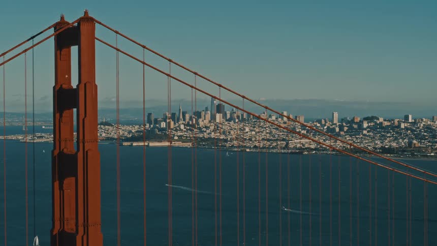 Boats sail past the golden gate bridge across from downtown San Francisco