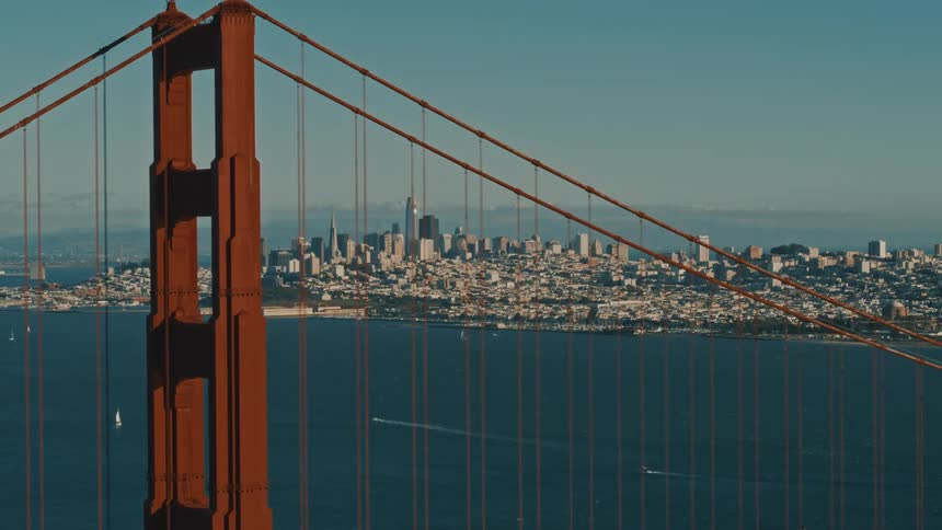 Aerial view of golden gate bridge and distant city skyscrapers and high rise buildings over the sea