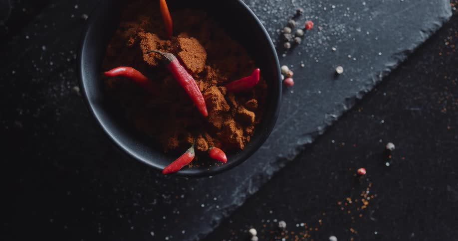 An aerial view of a bowl of chilies and spices on a counter