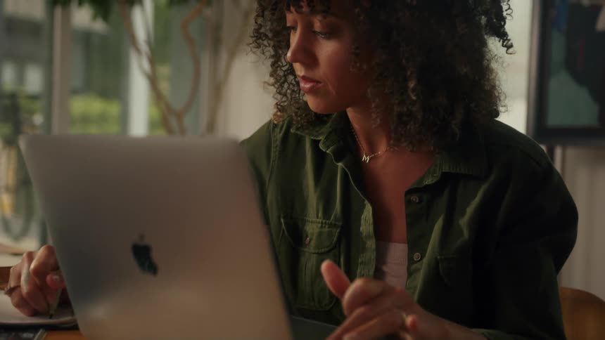 A woman is typing on her laptop and sitting indoors