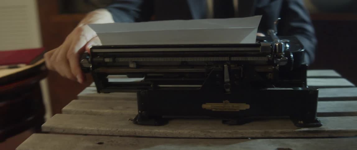 A man pulls the ribbon on the typewriter as he types