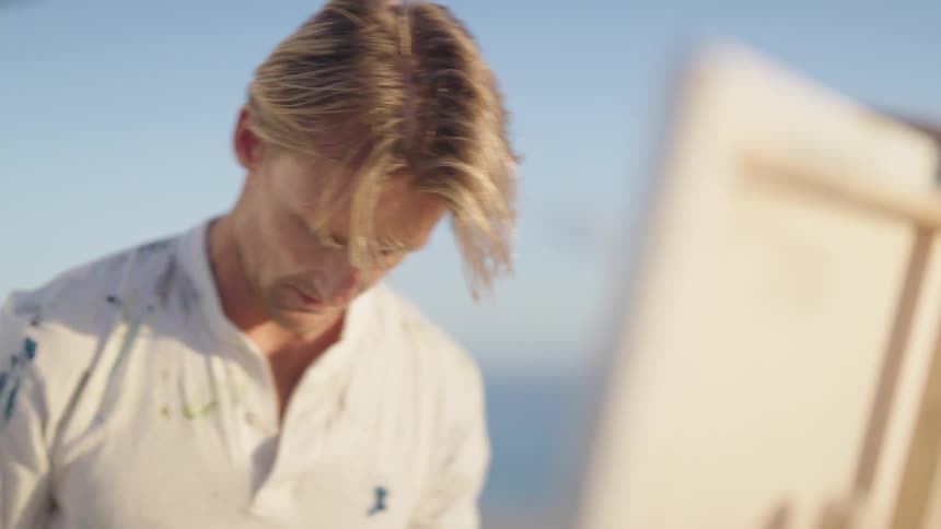 A man painting on a canvas outdoors