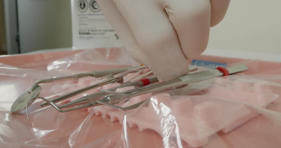 A technician in a dental office picks up an instrument
