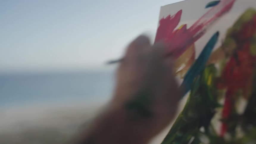 A man combines paint colors on a palette while painting on his patio