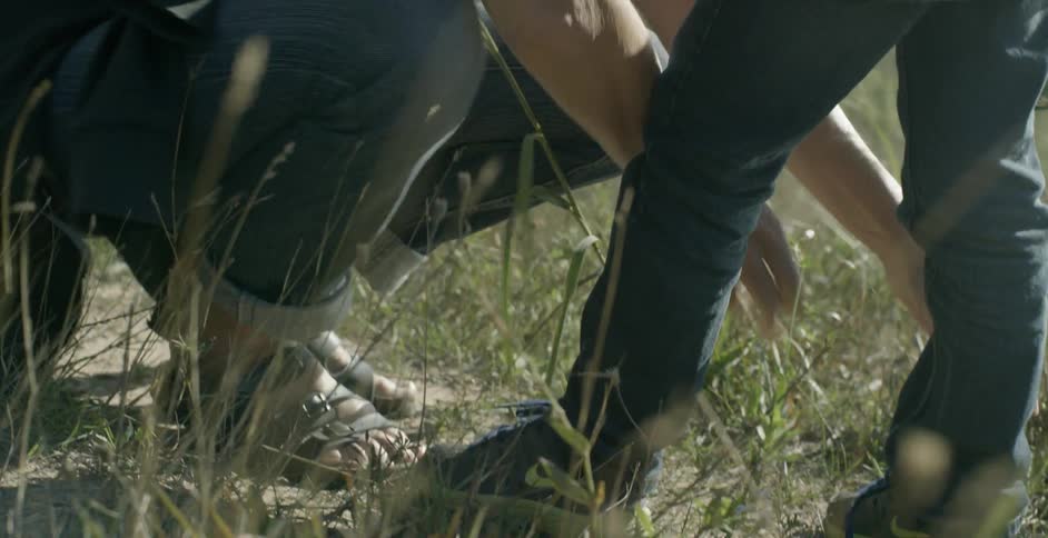 A woman ties her child's shoes while on a hike in the daytime