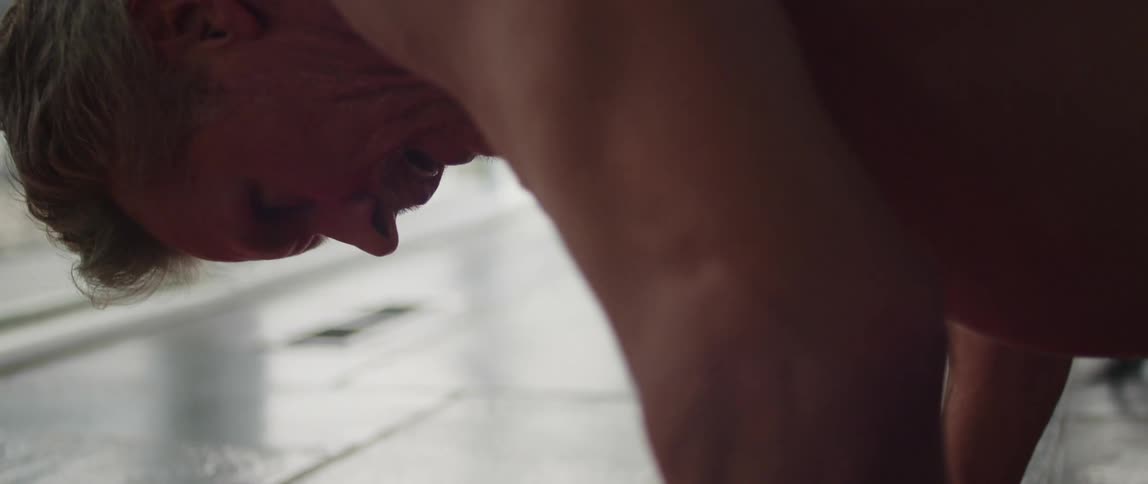 Topless muscular man does pushups on red yoga mat with determination