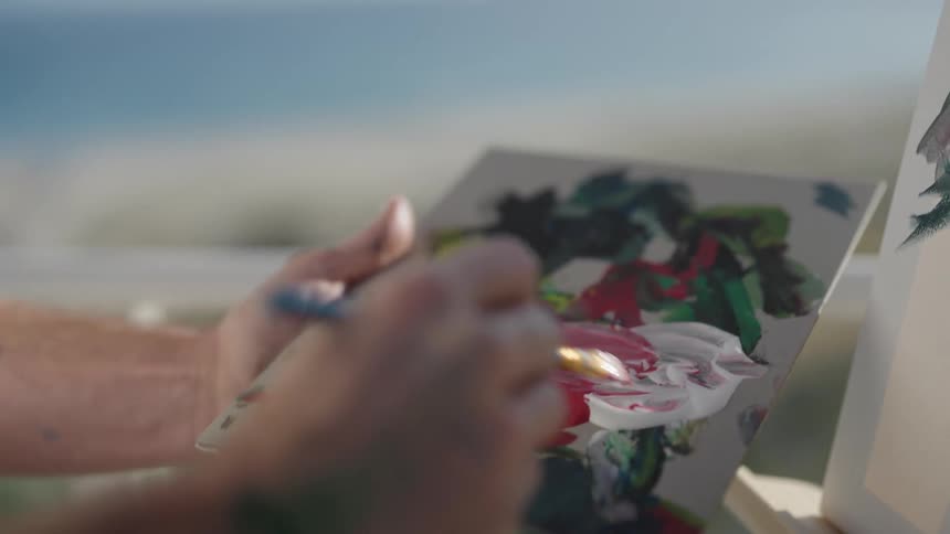 Close up view of a person painting on a canvas