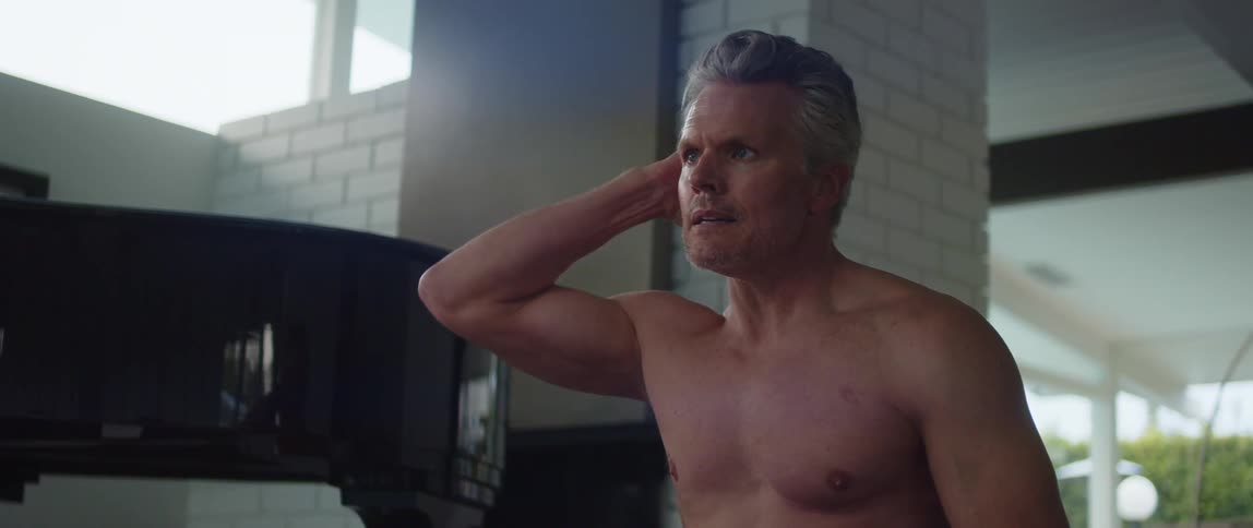 A man brushes his hair back with his hand