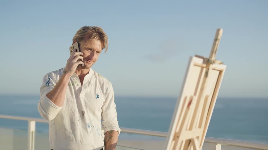 A man is talking on the phone next to a canvas