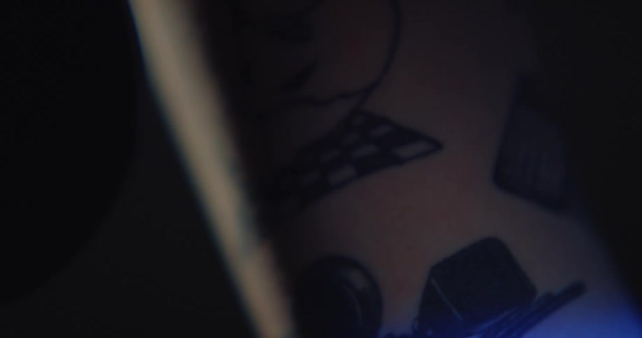 A light shines across a persons tattooed arm