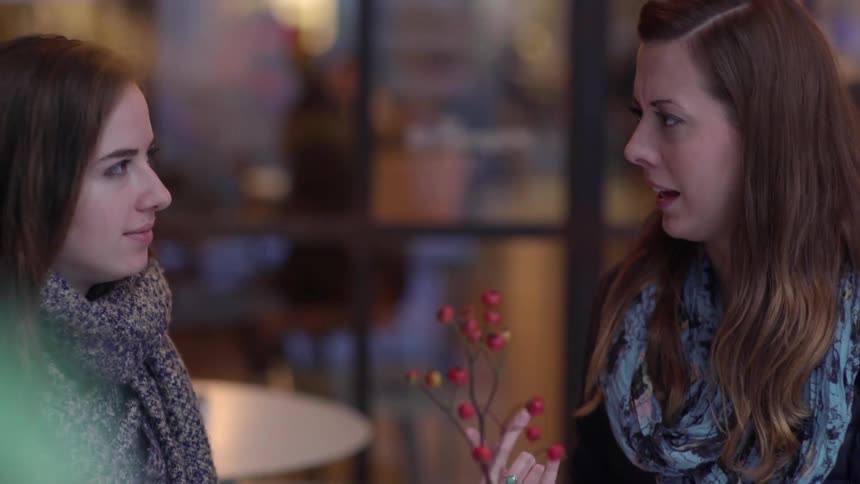 Women sit at a cafe table and have a conversation