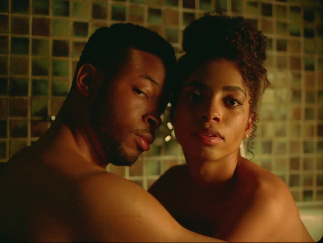 A man and woman sit in a bathtub and hug