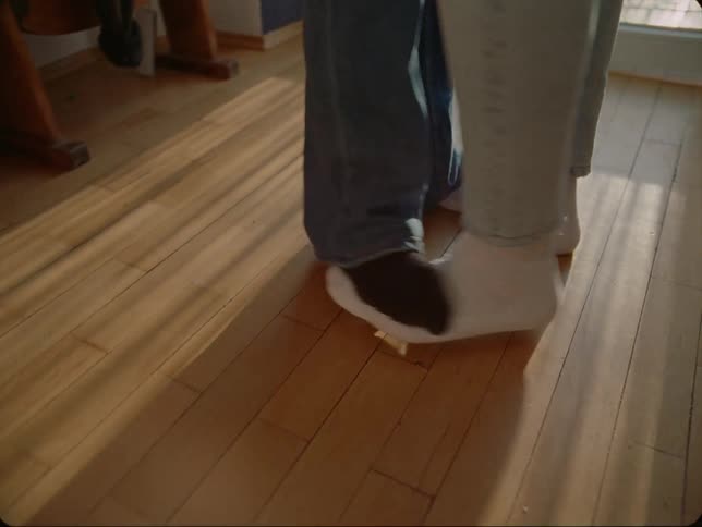 A couple dance at home with one person standing on their partners feet
