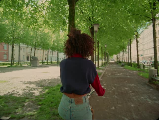 A woman is riding a bicycle through a city during spring