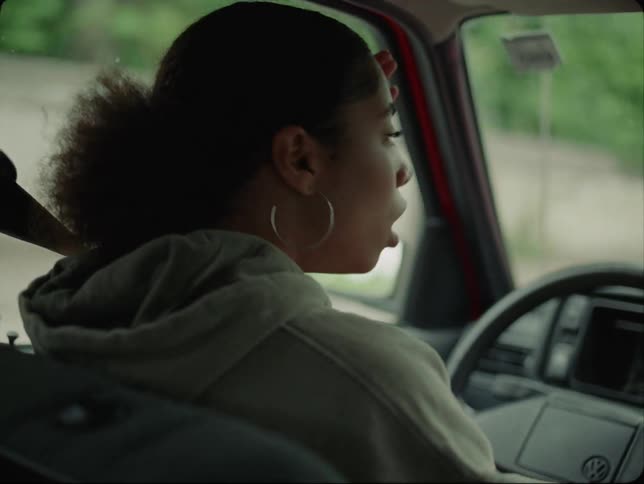A woman hits her hands on the steering wheel of the car that she is