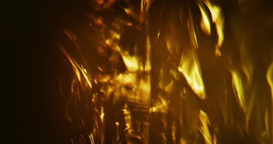 An amber glowing substance illuminates the darkness with bright golden light as it moves