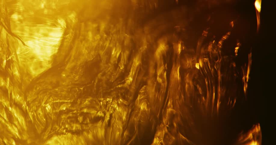 Amber waves of a glowing substance roll over the darkness with bright golden yellow light