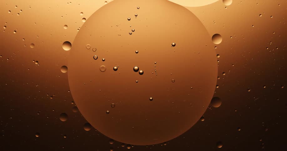 A droplet of liquid is suspended in another liquid and surrounded by smaller droplets