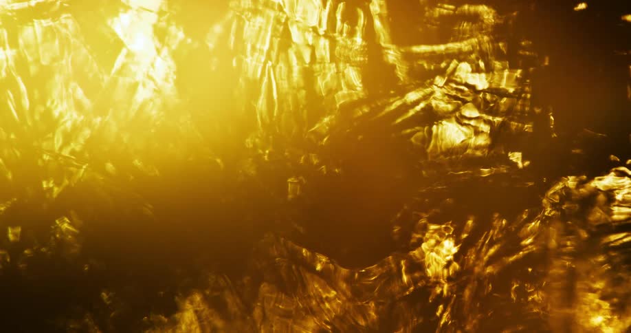 Bright orange light refracts through a rippling liquid to create a flame like image