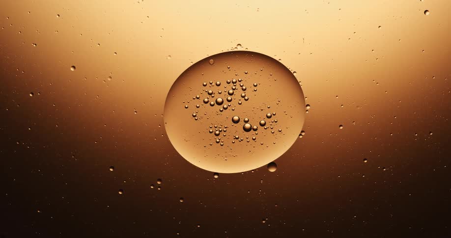 Bubble containing other bubbles elongates and separates into two against metallic background