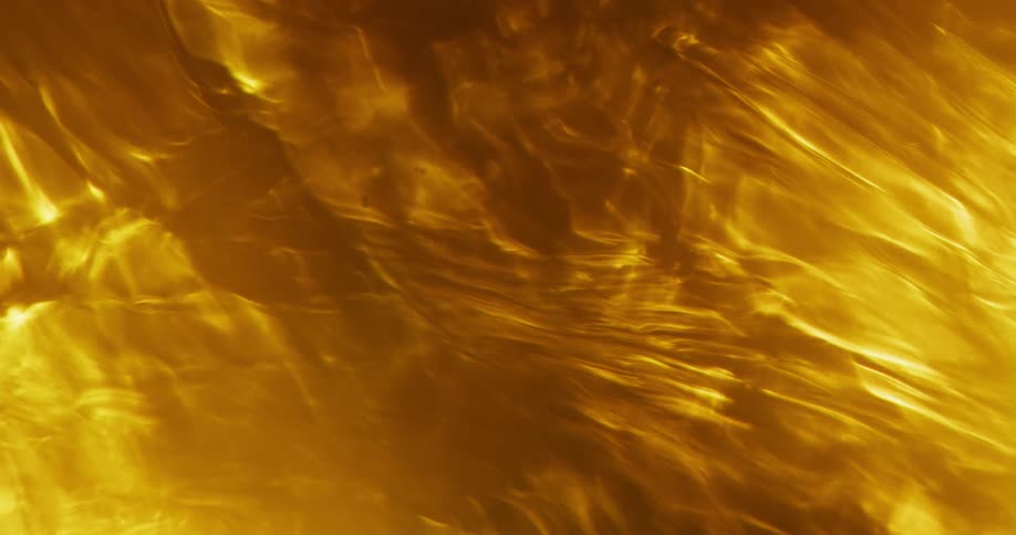 A liquid flows while it is illuminated by an orange light which makes it look like flames