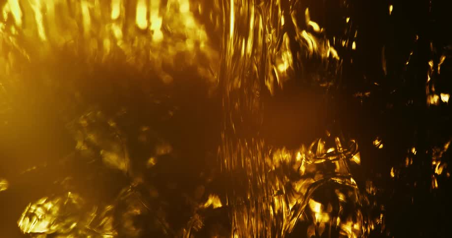 Thick amber liquid flows slowly downward partly in light and partly in shadow